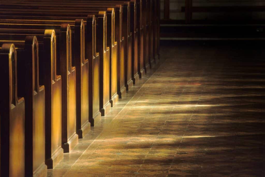 Bancs d’église éclairés par la lumière, symbole de Tradition vivante et de communion catholique