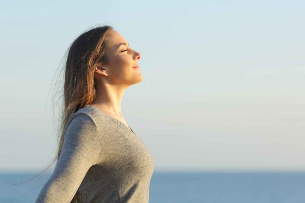 Femme les yeux fermés respirant face à la mer, image symbolique du Souffle dans Laisse la Vie respirer en toi